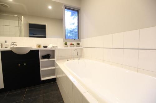洛恩洛恩豪华度假屋的白色的浴室设有浴缸和水槽。