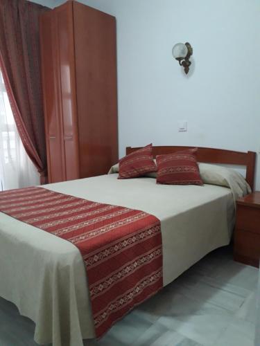 加的斯太阳中心旅馆的一间卧室配有一张带红色枕头的大床