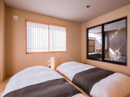 松山道后温泉八千代旅馆的带窗户的客房内的两张床