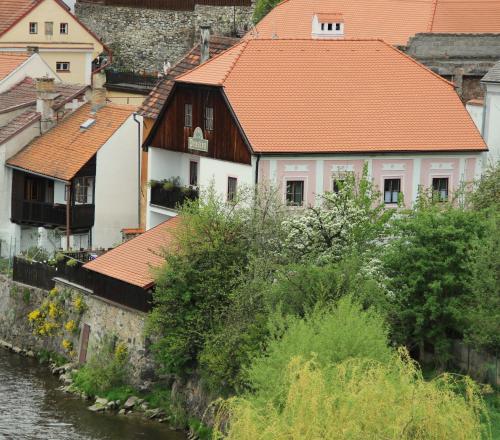 捷克克鲁姆洛夫普拉斯维卡119宾馆的一座有橙色屋顶的建筑物,毗邻一条河流