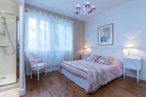 卡布勒通La Belle Vie Capbreton的一间卧室设有一张床、一个窗户和一个吊灯。