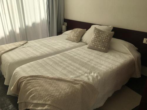 洛斯·亚诺斯·德·阿里丹White House Suite的一间卧室配有两张带白色床单和枕头的床。