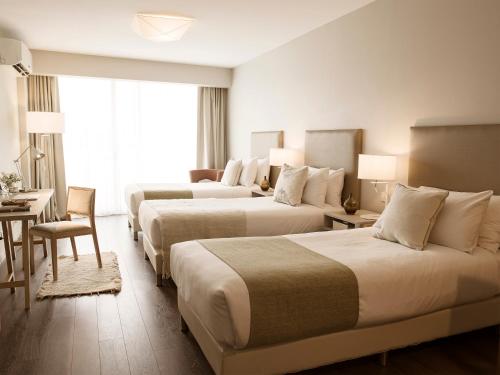 布宜诺斯艾利斯Dazzler by Wyndham Polo的酒店客房,设有三张床和一张桌子及椅子