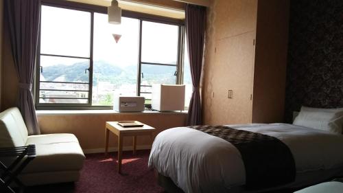 那智胜浦町胜浦日出日式旅馆的酒店的客房 - 带一张床、椅子和窗户