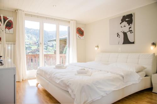 格林德尔瓦尔德Chalet D的白色的卧室设有一张白色大床和一个窗户。