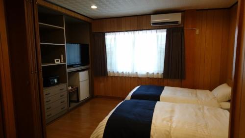 桑名市Minpaku Nagashima room2 / Vacation STAY 1036的一间卧室设有一张床、一个窗口和一台电视