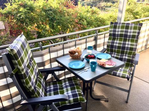 瓦尔内明德Fewo Mittelmole的阳台上配有一张桌子和两把椅子,并摆放着食物