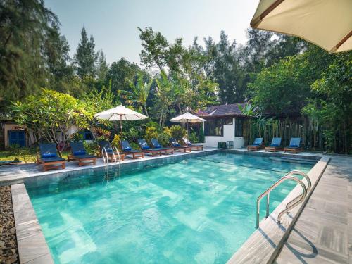 会安AIRA Boutique Hoi An Hotel & Villa的一个带椅子和遮阳伞的大型游泳池
