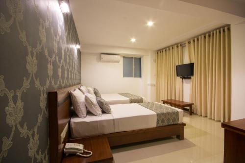 康提Ceyloni City Hotel的酒店客房,配有床和电视