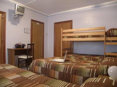 弗拉加Hostal Oasis的一间卧室配有两张床和一台笔记本电脑。