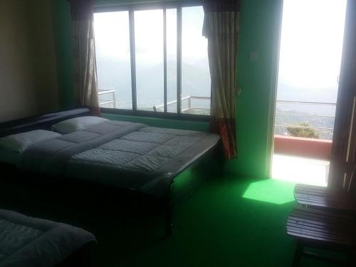 博卡拉Himalayan crown lodge的卧室在窗户前配有一张床