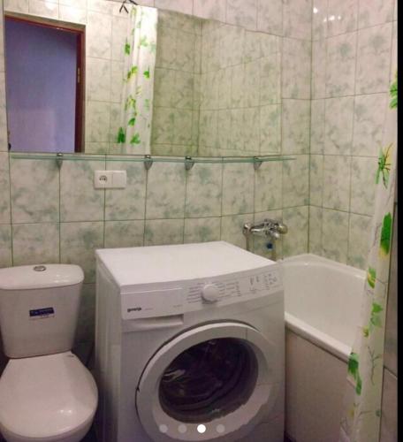 尼科波尔Apartment Shevchenka 154的浴室配有洗衣机、卫生间和浴缸。