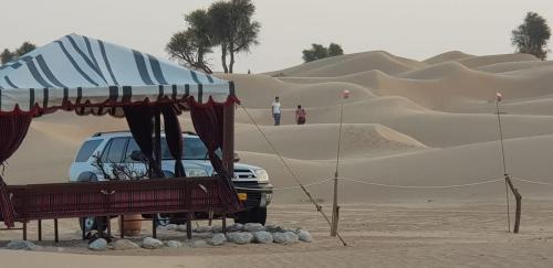 Fulayj al MashāʼikhLegend Desert camp的沙漠中一些沙丘附近的一个汽车
