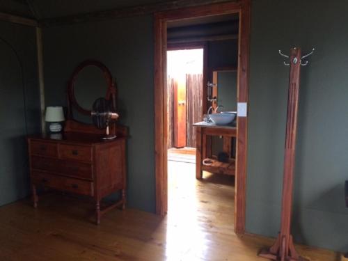 普利登堡湾Hillcrest Lodge Tents - Sandstone的一间设有镜子、木制梳妆台和镜子的客房