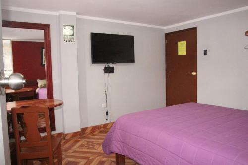 瓦拉斯Hostal Florencia的一间卧室配有紫色的床和一台平面电视