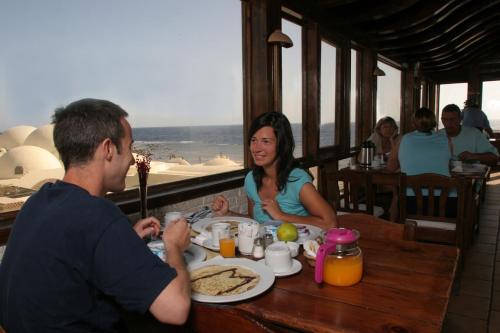 达哈布奈斯玛度假村的坐在餐桌旁吃食物的男人和女人