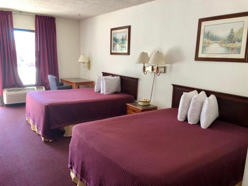KewaneeKewanee Motor Lodge的酒店客房,配有两张带紫色床单的床