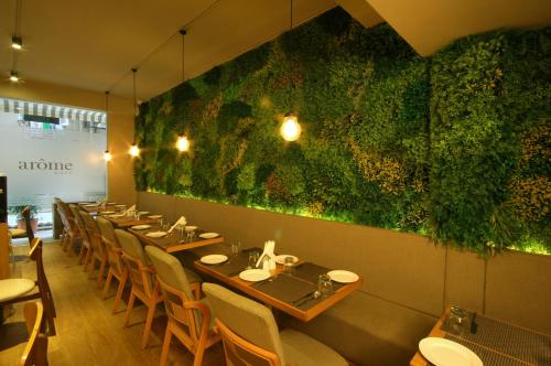 孟买Hotel Suncity Apollo, Colaba的餐厅的一排桌子,有绿色的墙壁