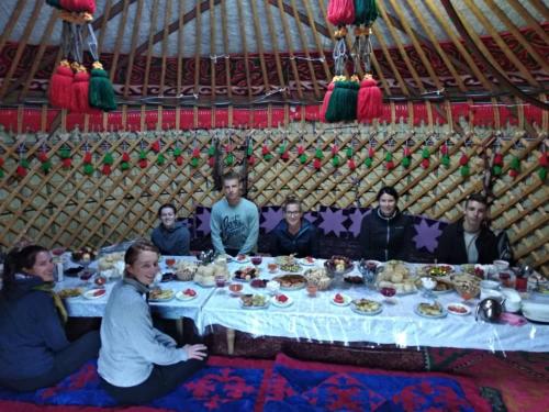 BagyshYurt Camp Azamat at Song Kol Lake的一群人坐在蒙古包的桌子旁