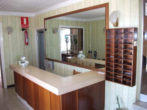弗拉加Hostal Oasis的浴室设有镜子和带葡萄酒瓶的吧台
