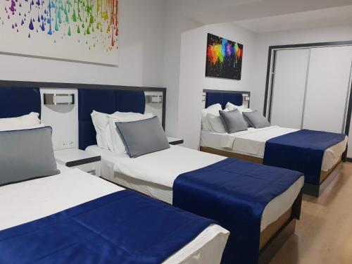 伊兹密尔Alican 2的酒店客房,配有三张带蓝色床单的床