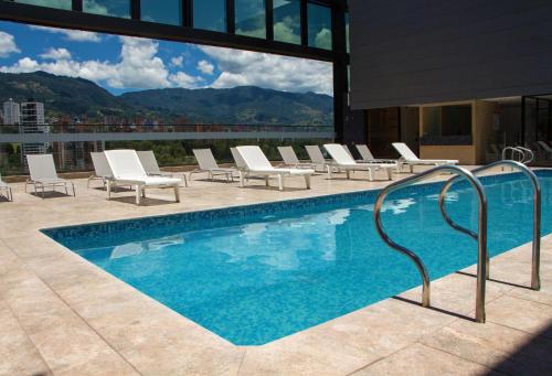 麦德林Hotel Estelar Square的一座带椅子的游泳池,享有大楼的景色