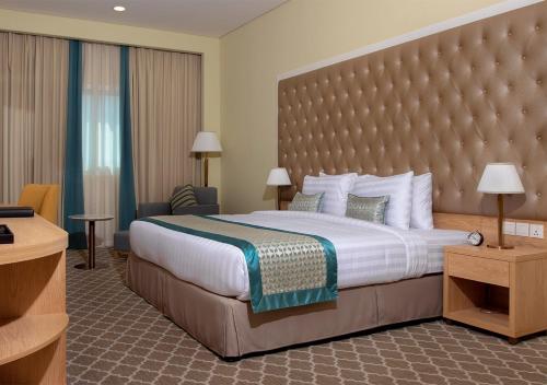 迪拜Jacob's Garden Hotel的酒店客房设有一张大床和大型床头板