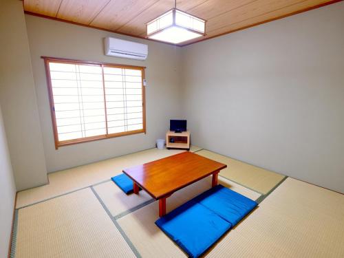 KaminatoKokumin Shukusha Sun Marina的客厅配有桌子和蓝色垫子