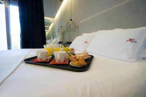 雅典X Dream Hotel-Adults Only的床上的食品托盘,配以橙汁