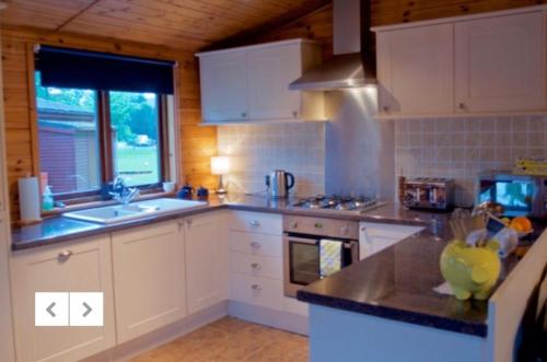 罗厄德南Caol Gleann Lodge的厨房配有白色橱柜、水槽和窗户。