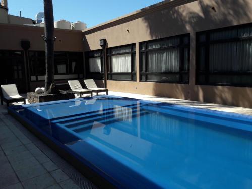 康考迪亚Cristobal Hotel Boutique的一座蓝色游泳池,旁边是一座建筑,配有两把椅子