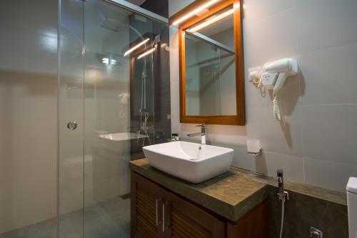 康提Ceyloni City Hotel的一间带水槽、镜子和淋浴的浴室