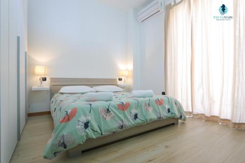 滨海波利尼亚诺Pausa Mare Apartment的白色卧室配有一张带花卉床罩的床
