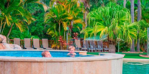 阿沃卡海滩阿沃卡棕榈树酒店的度假村游泳池的两名儿童