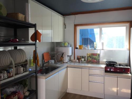 济州市Jeju Guesthouse的厨房配有白色橱柜、水槽和窗户。