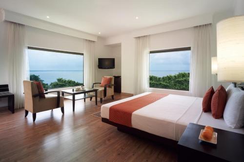 尼甘布Vivanta Colombo, Airport Garden的一间卧室配有一张床、一张书桌和两个窗户。