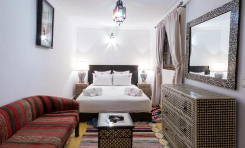 马拉喀什Riad Ramz的一间卧室配有一张床、一张沙发和一面镜子