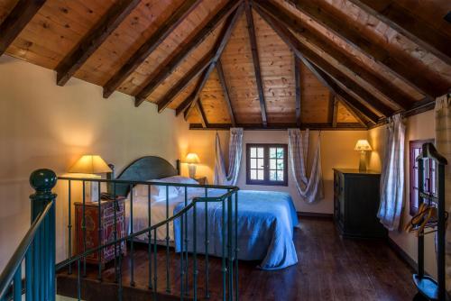 Arco de São JorgePestana Quinta do Arco Nature & Rose Garden Hotel的一间带一张床的卧室,位于带木制天花板的房间内