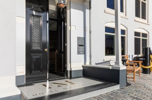 马斯劳斯Hotel Maassluis的白色建筑上带人行道的黑色门