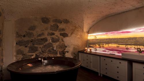 TaageperaCastle Spa Wagenküll的一间带大浴缸和石墙的浴室