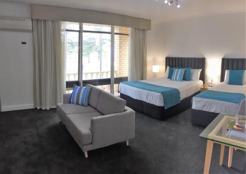 阿德莱德恩塞纳达套房汽车旅馆 的酒店客房带两张床、一张沙发和椅子