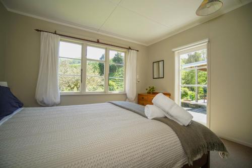 TinirotoMahaanui Cottage Farmstay的一间卧室设有一张大床和两个窗户