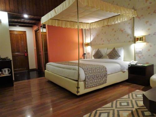 西姆拉西姆拉蜜月酒店的一间卧室,卧室内配有一张天蓬床