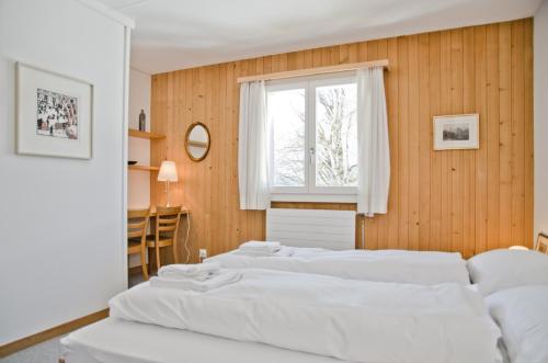 格林德尔瓦尔德Apartment Nussbaum - GRIWA RENT AG的一间卧室设有三张白色的床和窗户