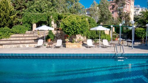 干尼亚仙女座别墅酒店的一个带桌椅和遮阳伞的游泳池