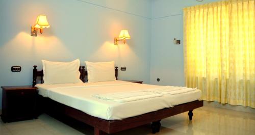 可瓦兰Ganesh Ayurveda Holiday Home bed and breakfast的一张位于带两盏灯和一扇窗户的房间的床铺