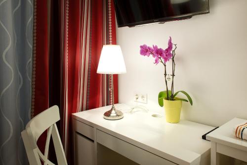 维也纳Pension am Wienfluss的一张带灯的白色书桌和紫色花