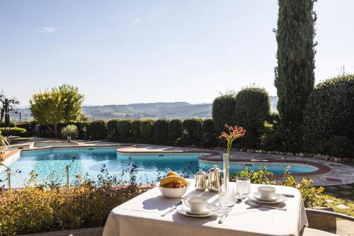 圣吉米纳诺Relais Santa Chiara Hotel - Tuscany Charme的一张桌子,上面有一碗水果,放在游泳池边