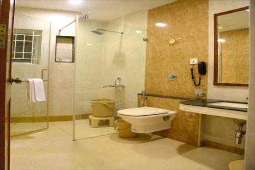 库姆巴科纳姆拉亚格兰德酒店的一间带卫生间和玻璃淋浴间的浴室