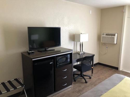 长滩长滩酒店的酒店客房配有一张书桌、一台电视和一张床